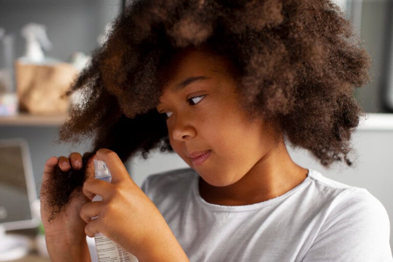 Enfant démêlant ses cheveux crépus.